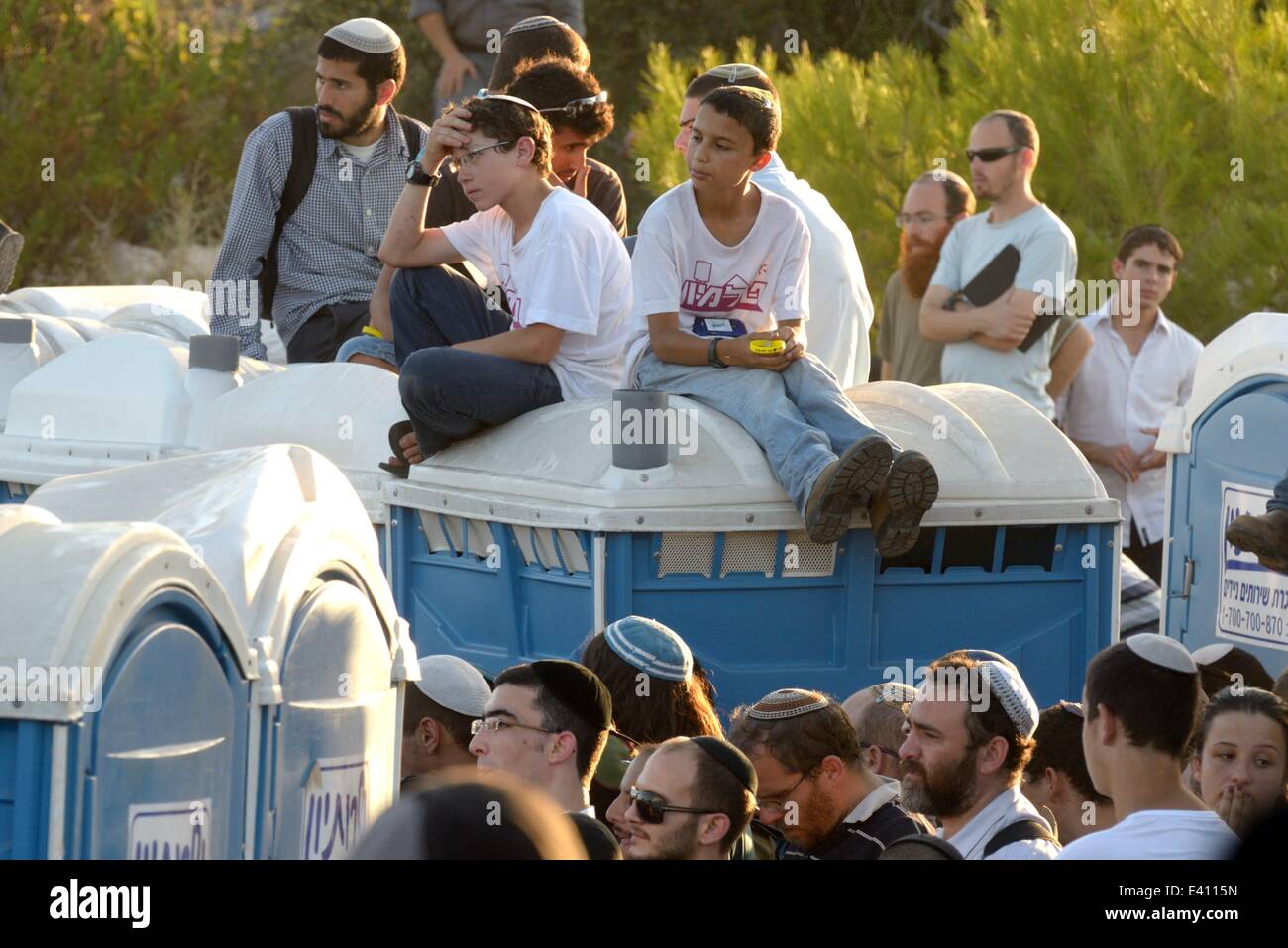 Modi'In, Israel. 1st July, 2014. Israeli teenagers are sitting atop mobile toilets during the funeral of the three kidnapped Israeli teenagers. Thousands of Israelis attended the funeral of three Israeli teenagers, Gil-Ad Shaer, Naftali Fraenkel, and Eyal Yifrah, who were kidnapped 19 days ago. The bodies of the three Israeli teenagers have been found, it was announced Monday night. The bodies were found north of the Palestinian town Halhul, just north of Hebron. (Credit Image: Credit:  Gili Yaari/NurPhoto/ZUMA Wire/Alamy Live News) Stock Photo