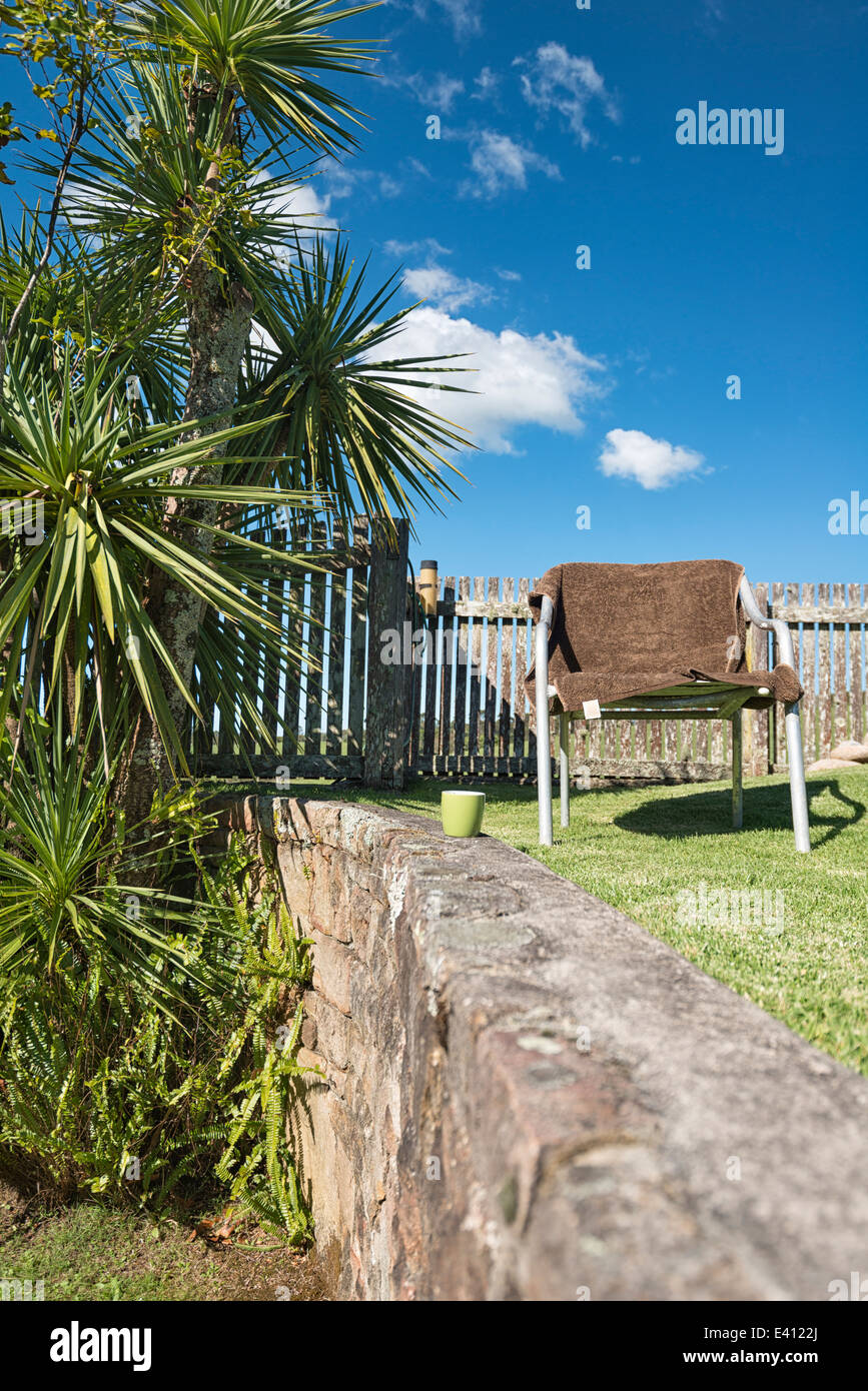 Australia, New South Wales, Dorrigo,  chair with towel and cabbage tree, Cordyline australis, in the garden Stock Photo