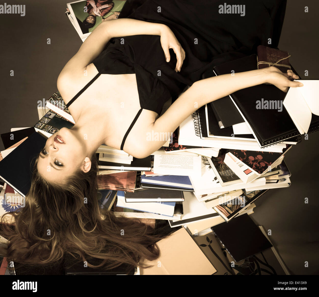 Portrait of young woman lying on pile of books Stock Photo - Alamy