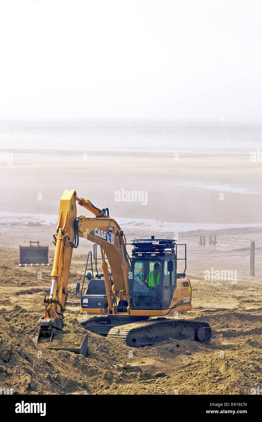 Excavator digging sand on beach in sea mist Stock Photo Alamy