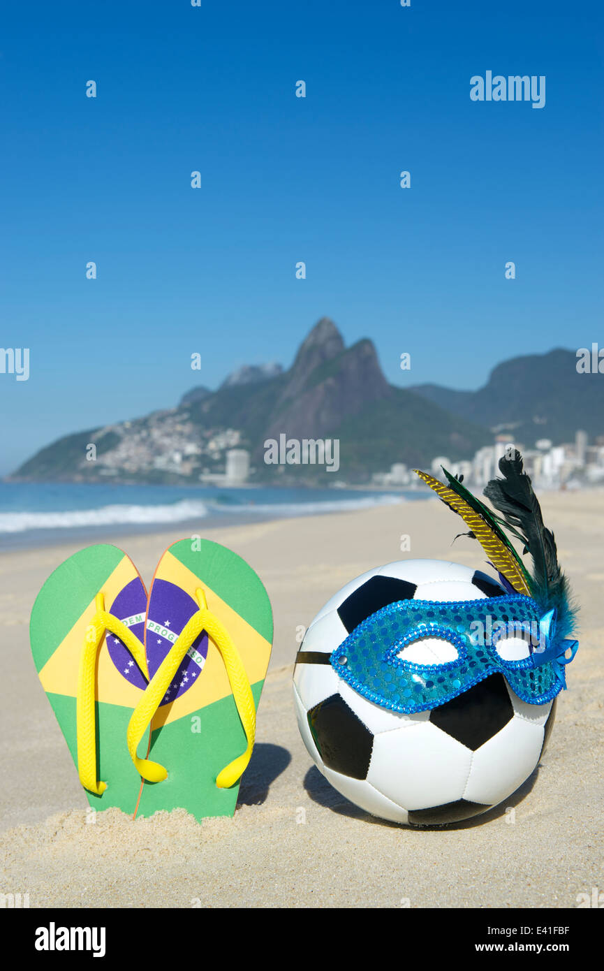 Soccer theme Rio Carnival football wearing sparkly mask with Brazil flag flip flops on Ipanema Beach Stock Photo