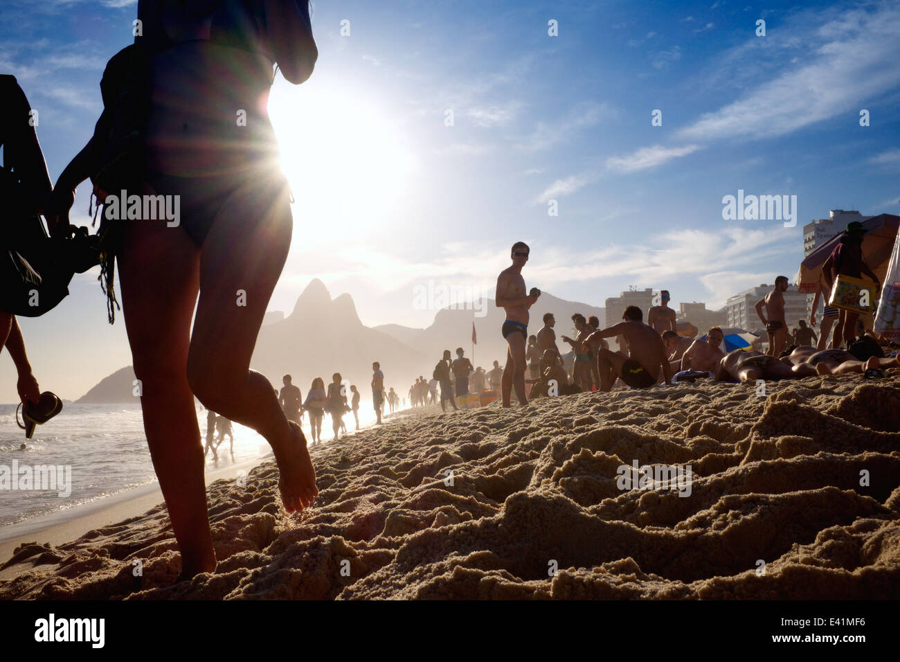 Brazilian woman in bikini walking on the shore in bright sunset at