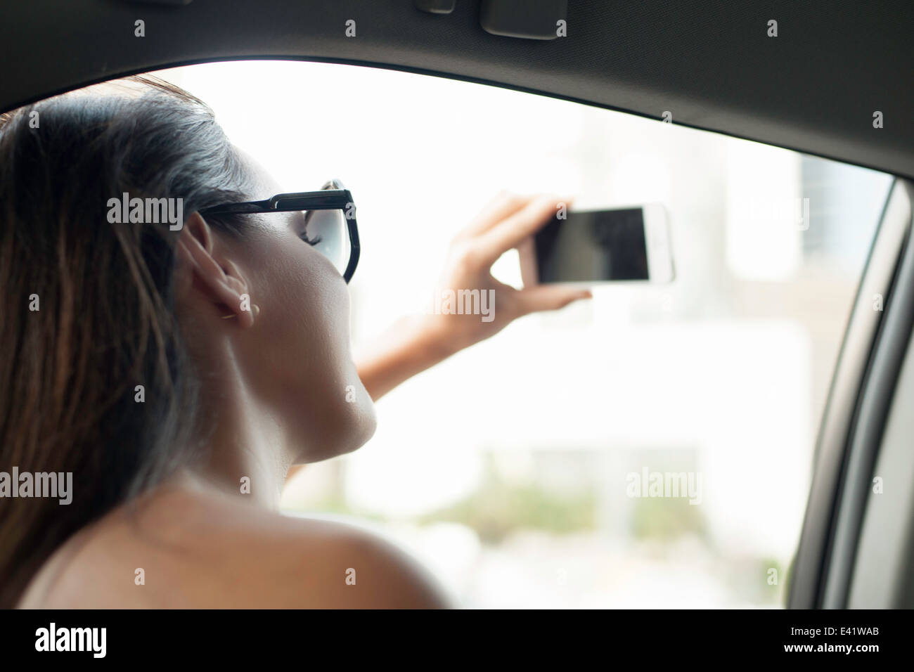 Young woman photographing with smartphone from taxi window Stock Photo