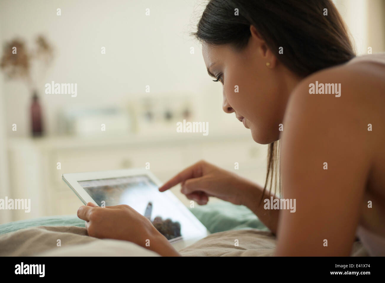 Young woman lying on bed using digital tablet Stock Photo
