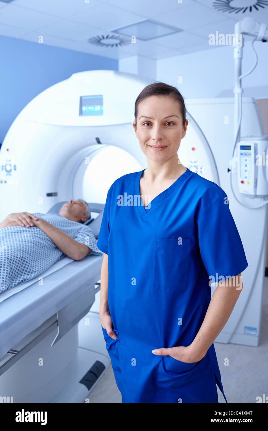 Radiographer standing in front of man going into CT scanner Stock Photo