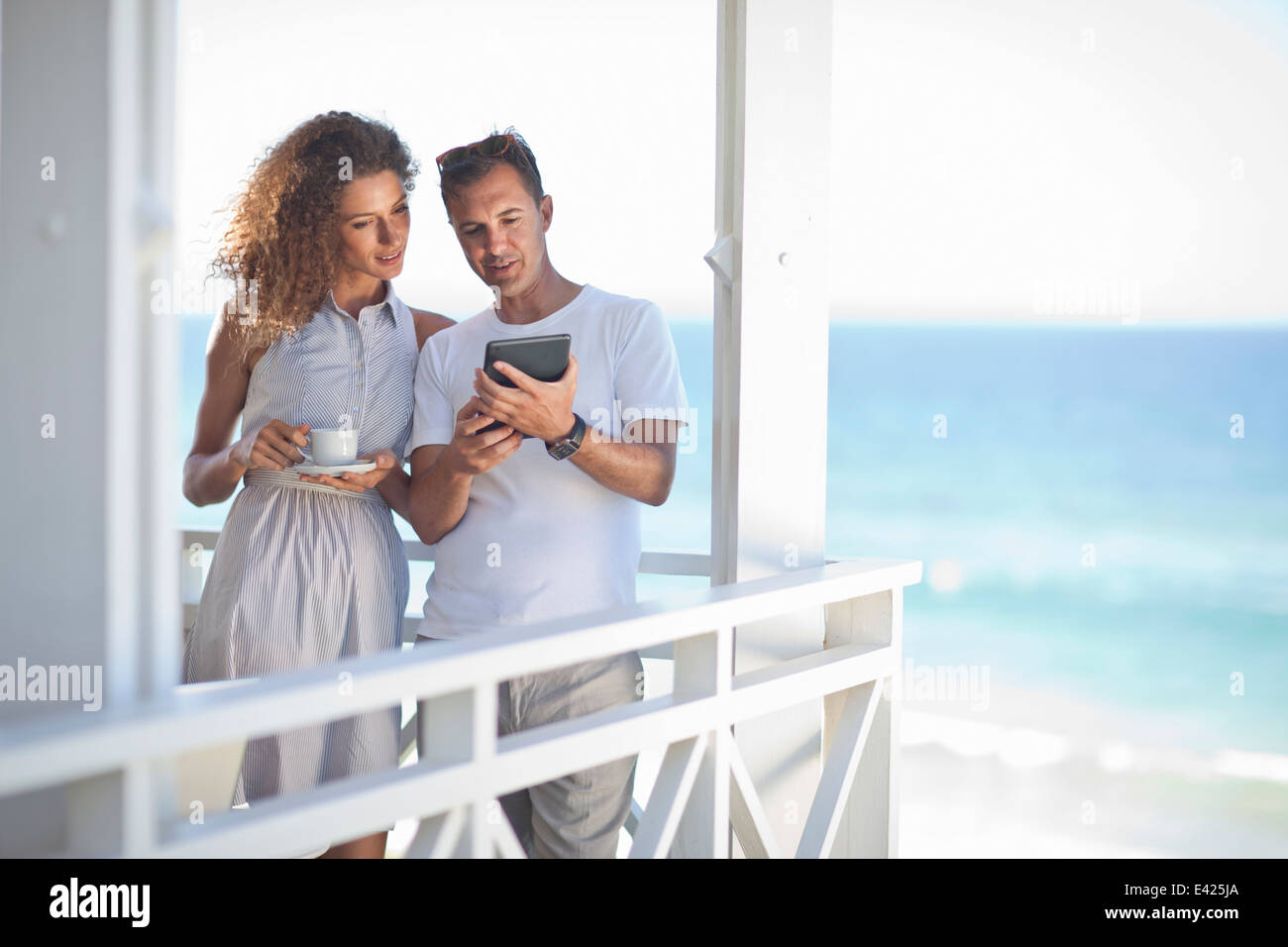 Couple looking at digital tablet on beach house balcony Stock Photo