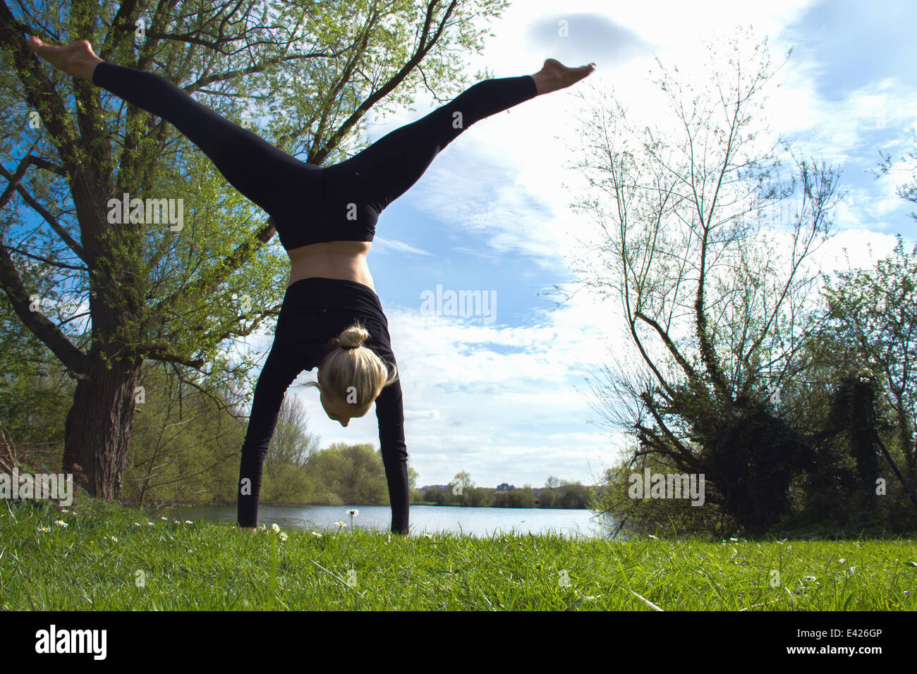 Young female dancer poised in handstand near lake Stock Photo