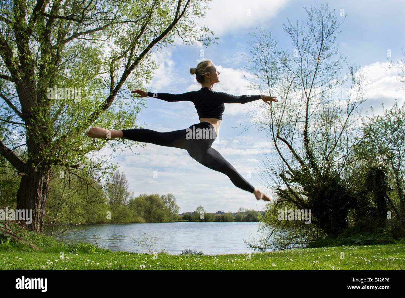 Young female dancer jumping mid air near lake Stock Photo