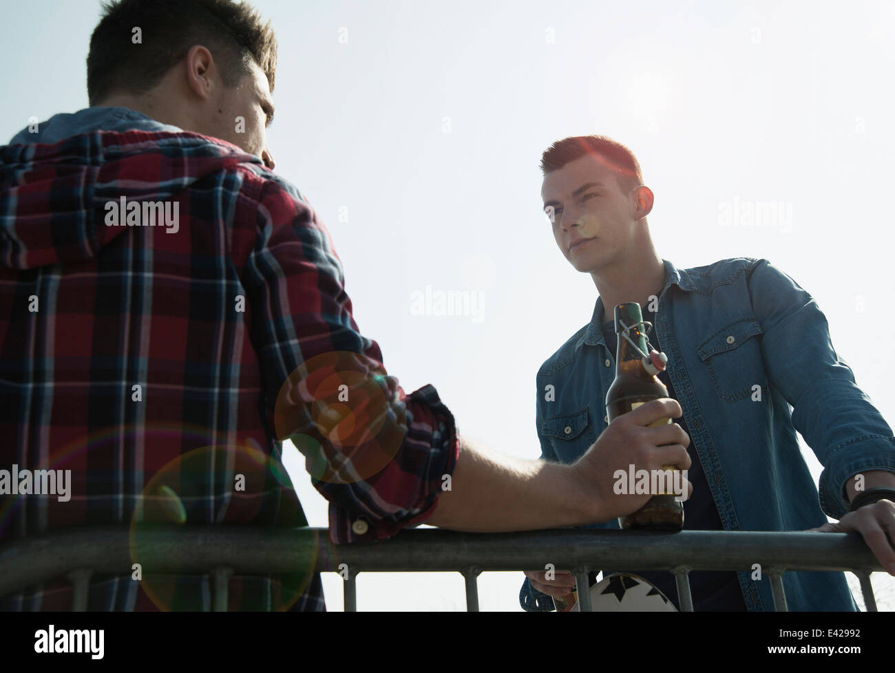 Young men in skatepark, drinking bottle of beer Stock Photo