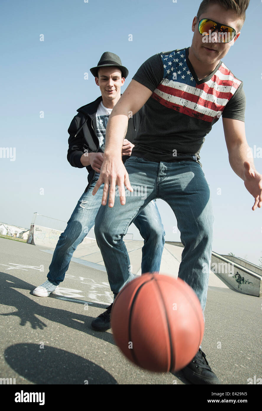 Young men playing basketball in skatepark Stock Photo