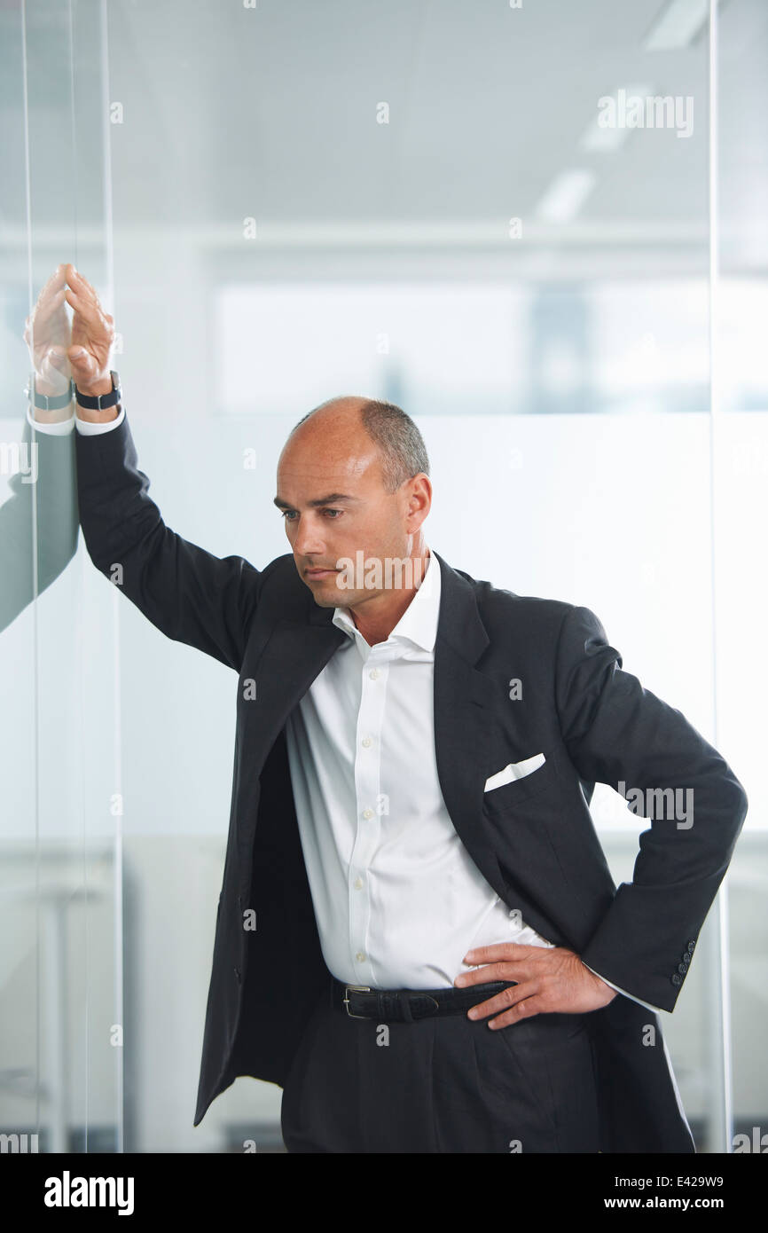 Businessman contemplating against reflective wall Stock Photo