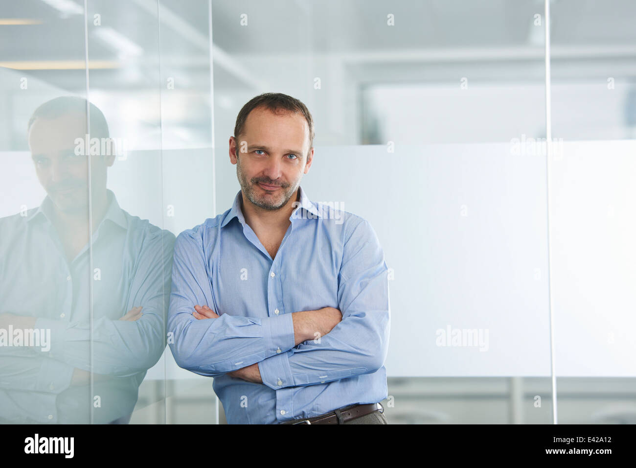 Businessman leaning against reflective wall Stock Photo