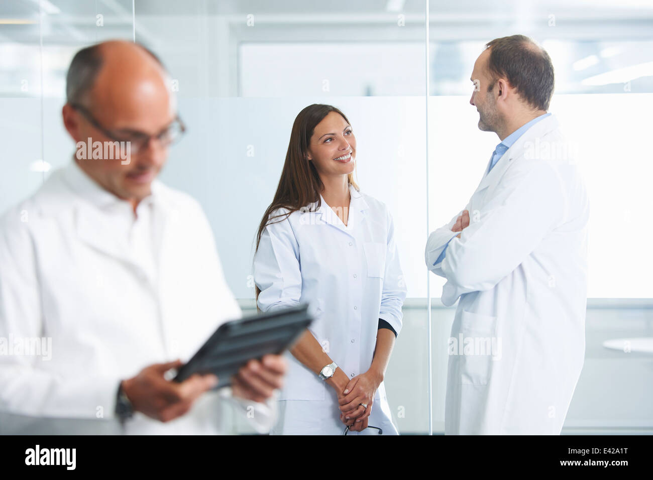 Male doctor using digital tablet, colleagues in background Stock Photo