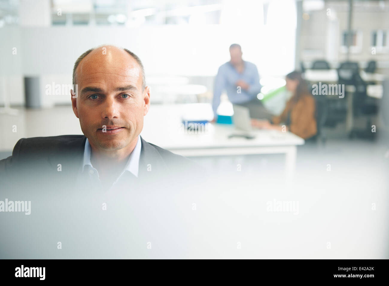 Man looking at camera, couple in background Stock Photo