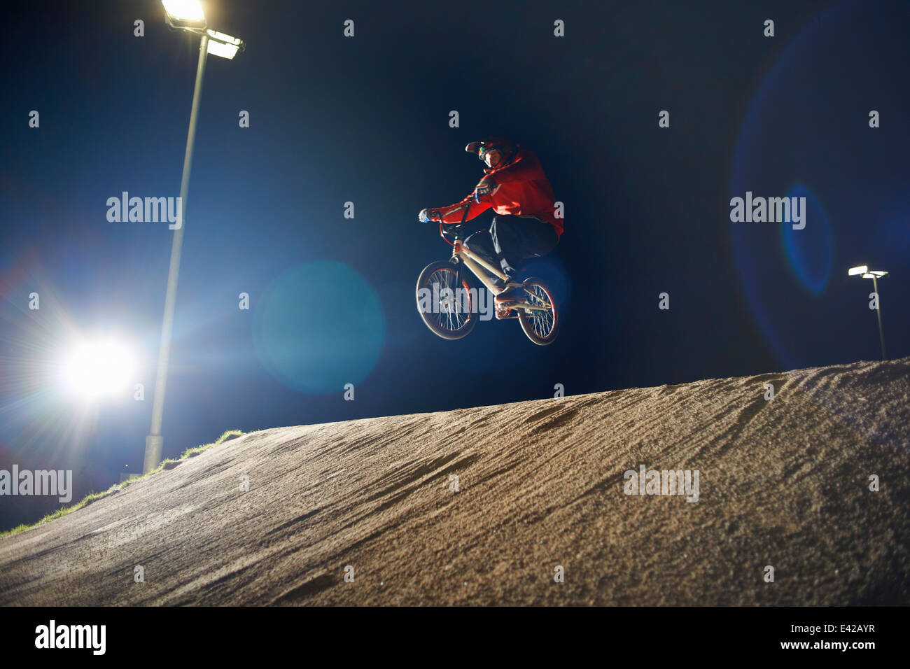 BMX-cyclist jumps his bike at night time Stock Photo