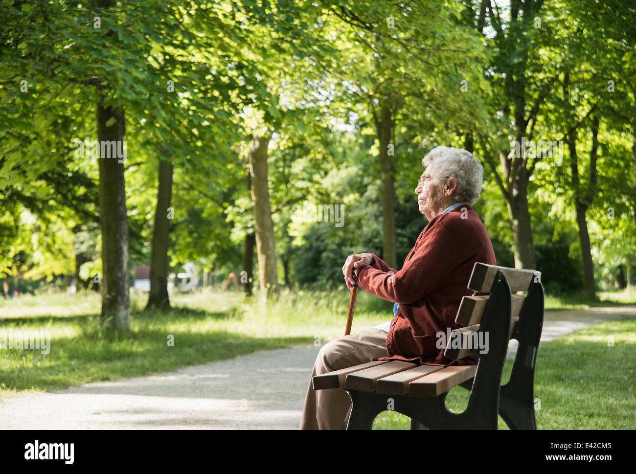 Senior woman sitting on park bench Stock Photo