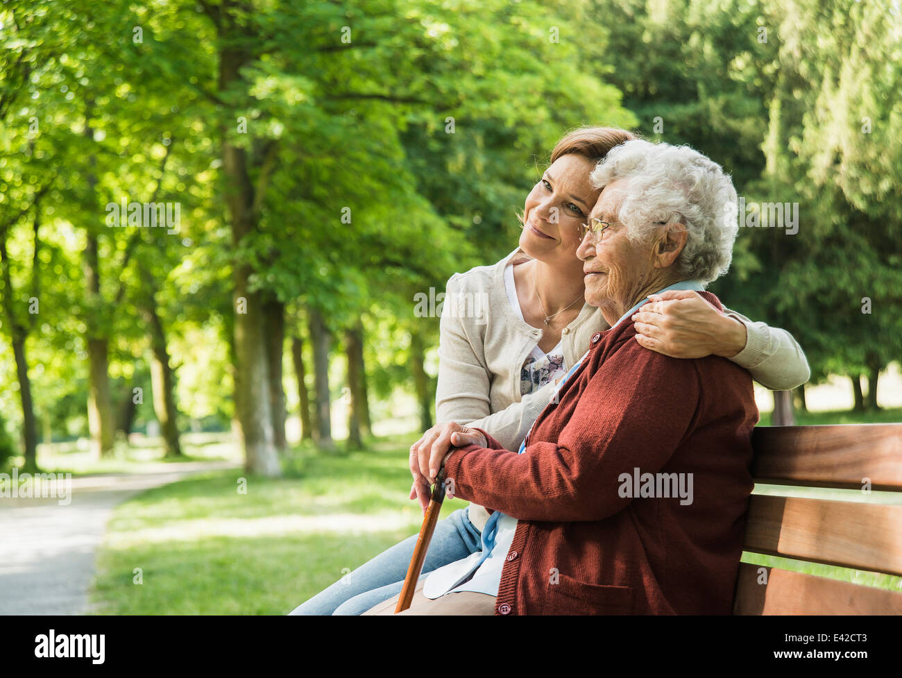 Senior woman sitting on park bench with granddaughter Stock Photo - Alamy