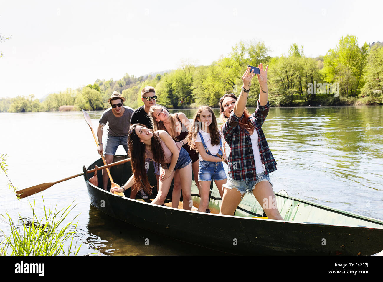 Group of friends in a row boat taking photo of themselves Stock Photo