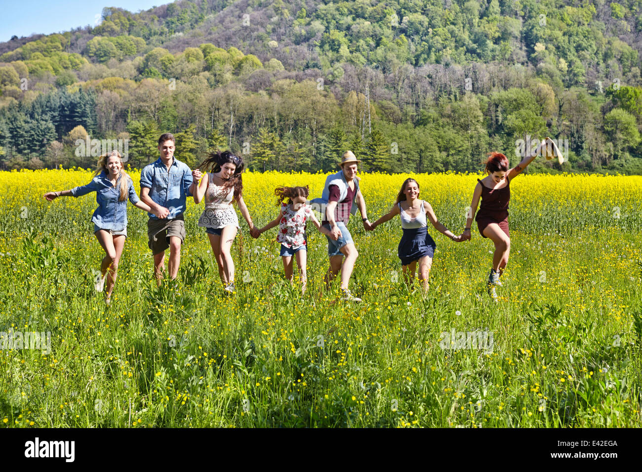 Group of friends running in field Stock Photo
