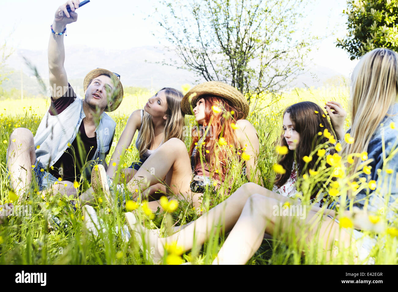 Group of friends sitting in grass photographing themselves Stock Photo