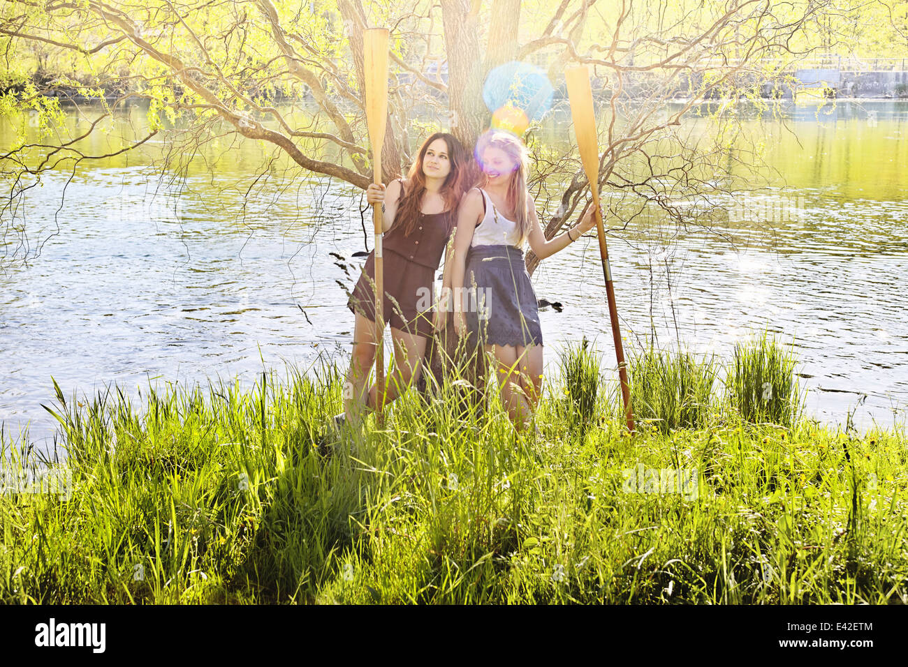 Young women holding oars by water Stock Photo