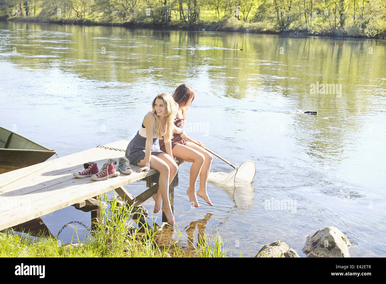 Young women sitting on jetty Stock Photo
