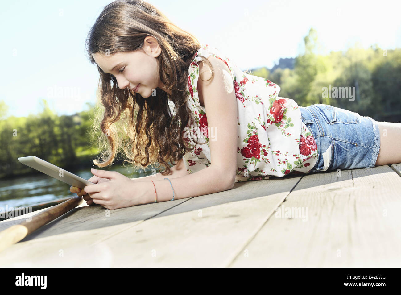 Girl using digital tablet on jetty Stock Photo