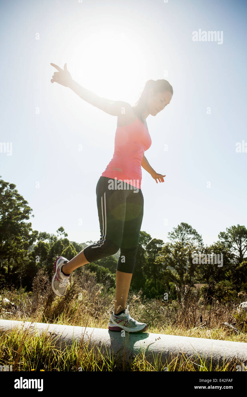 Female jogger balancing on pipe Stock Photo