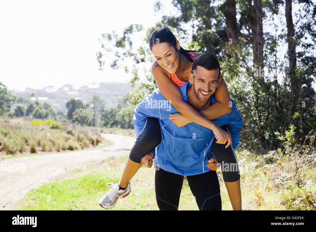 Female jogger riding piggyback on man Stock Photo