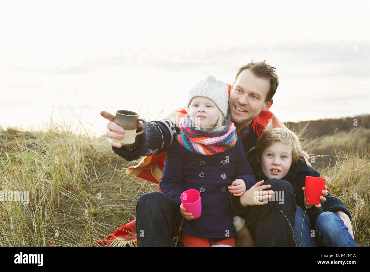 Smiling mid adult man with daughter and son on sand dunes Stock Photo