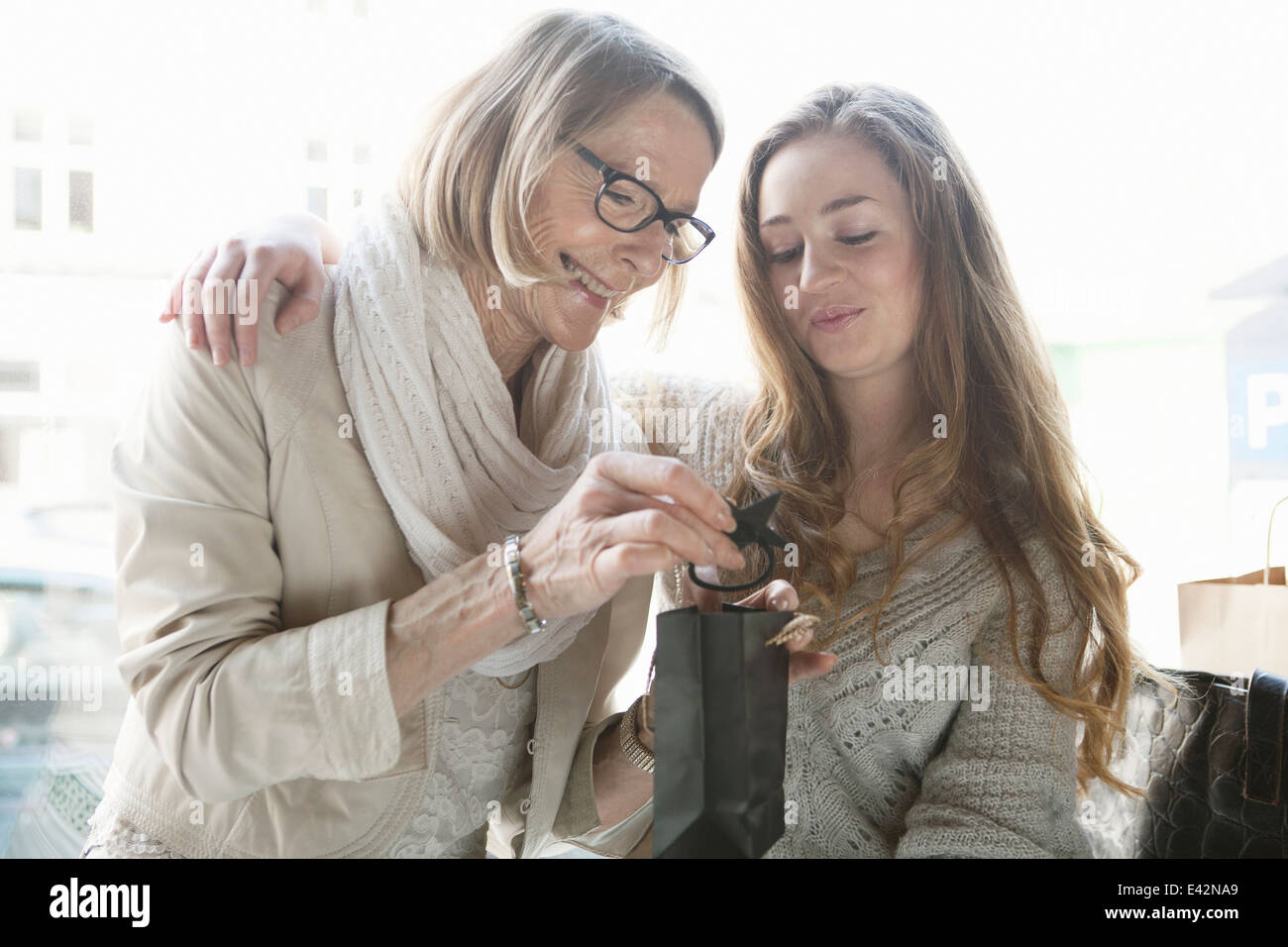Senior woman and granddaughter admiring shopping in cafe Stock Photo