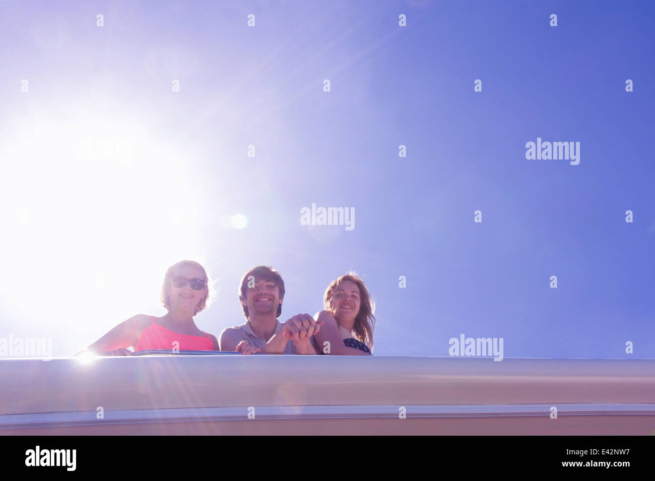 Portrait of three adult friends looking down from yacht Stock Photo