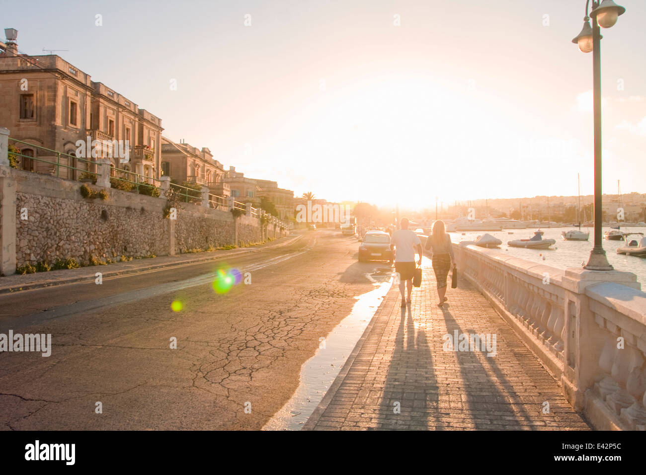 Couple strolling along harbor at sunset, Ta' Xbiex, Gzira, Malta Stock Photo