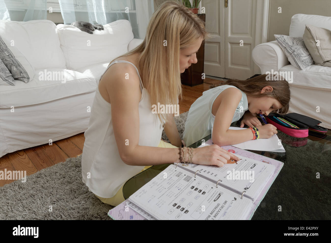 Mother helping daughter with homework on coffee table Stock Photo