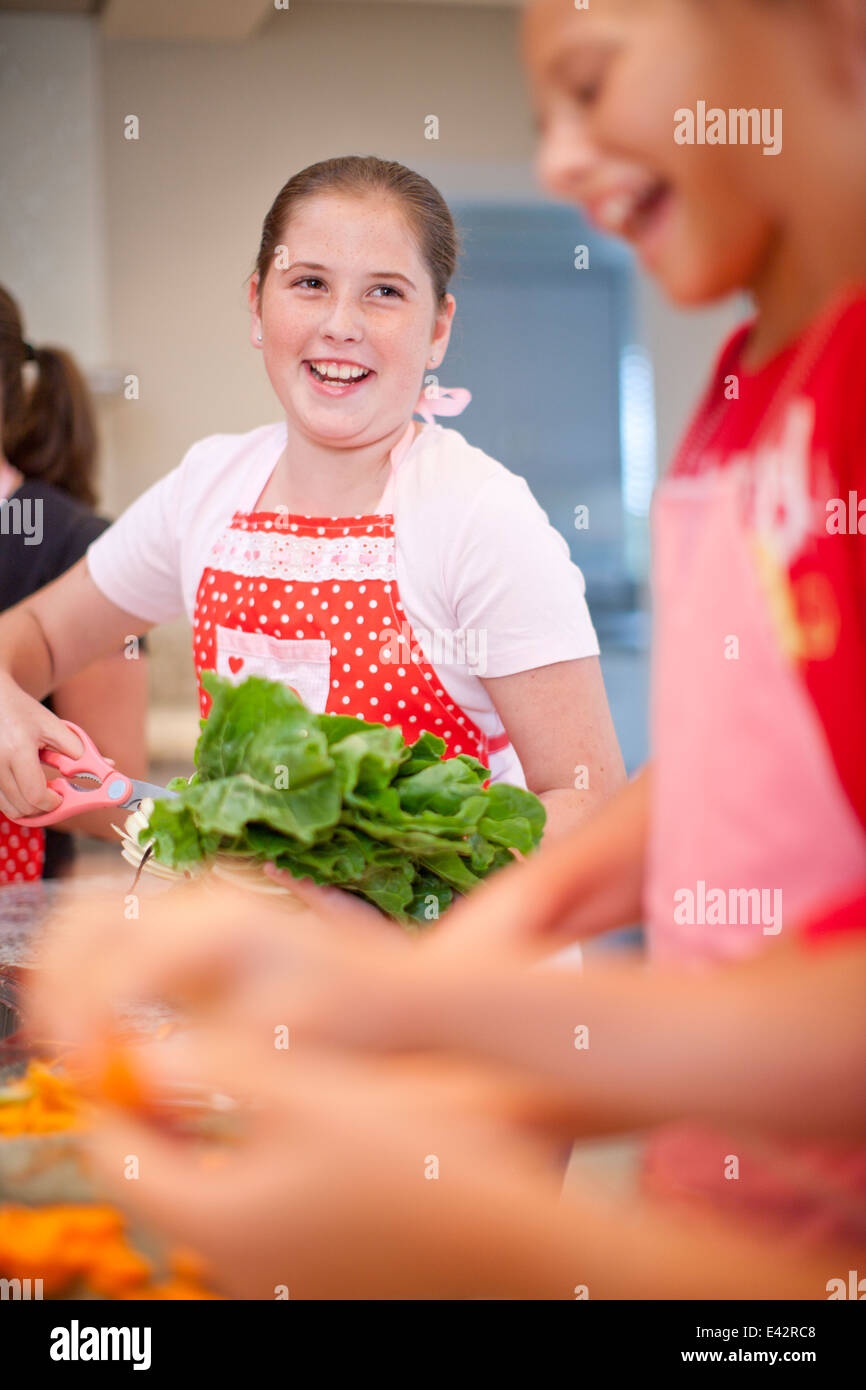 Teenage girls preparing vegetables in kitchen Stock Photo