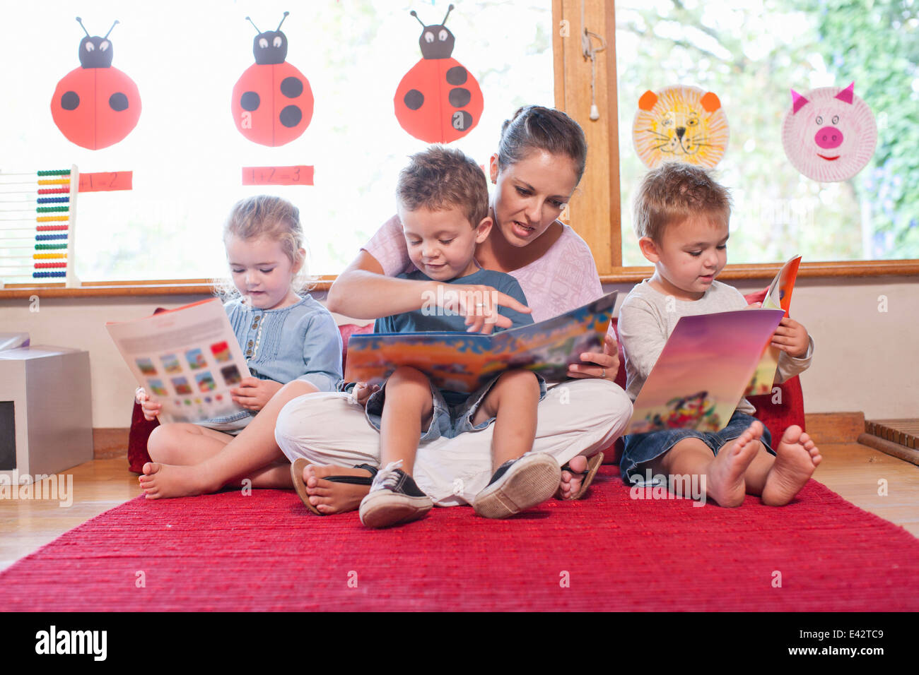 Teacher and pupils reading story books at nursery school Stock Photo