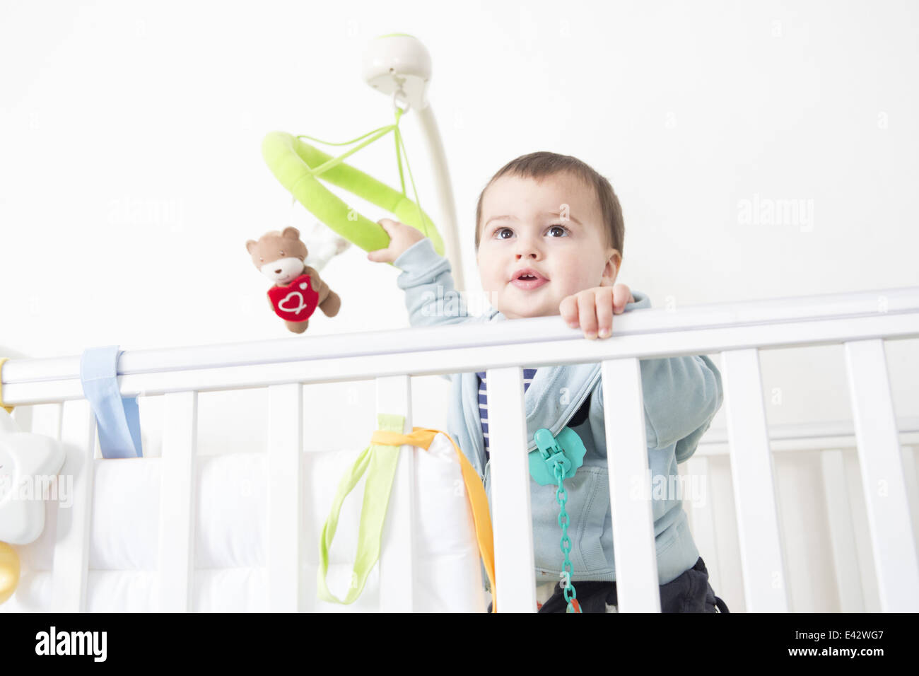 Alert baby boy gazing out from crib Stock Photo