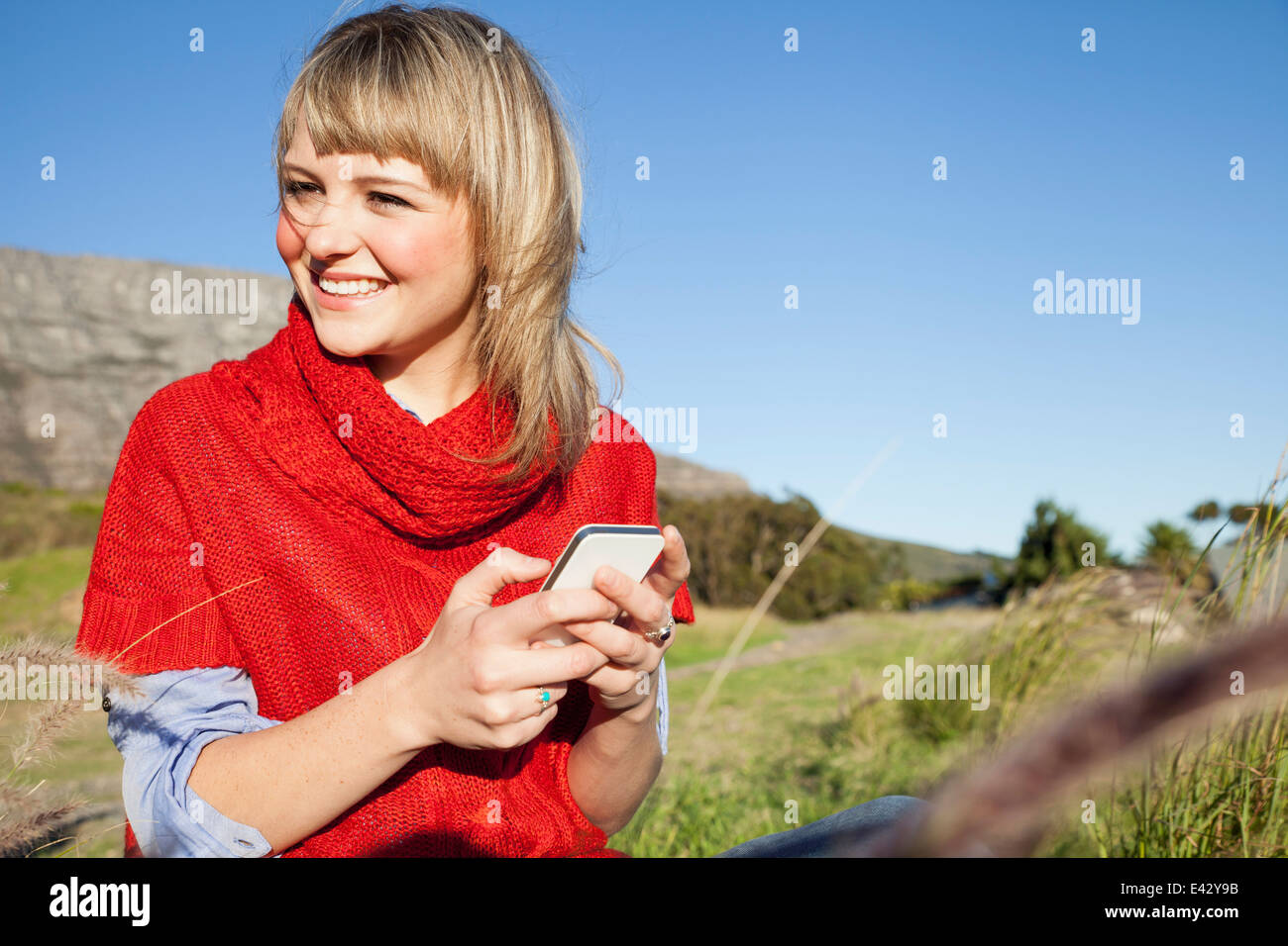 Young woman texting on smartphone in field Stock Photo