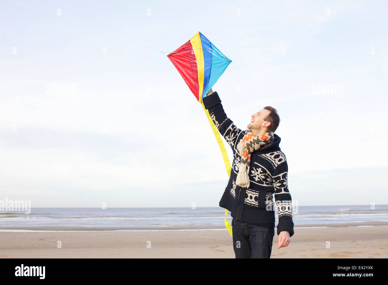 Mid adult man holding up kite on beach, Bloemendaal aan Zee, Netherlands Stock Photo