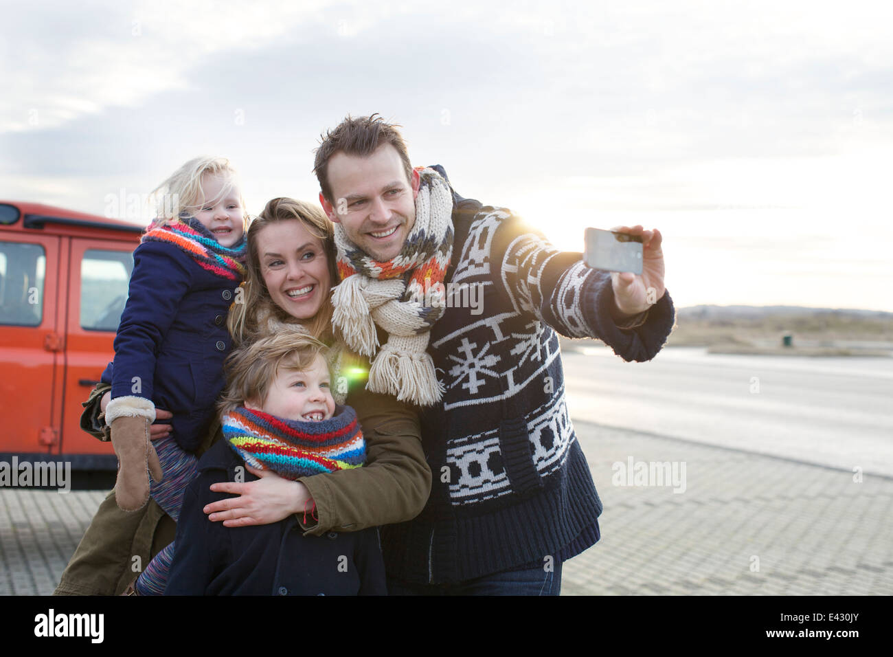 Mid adult man taking a family selfie in coastal parking lot Stock Photo