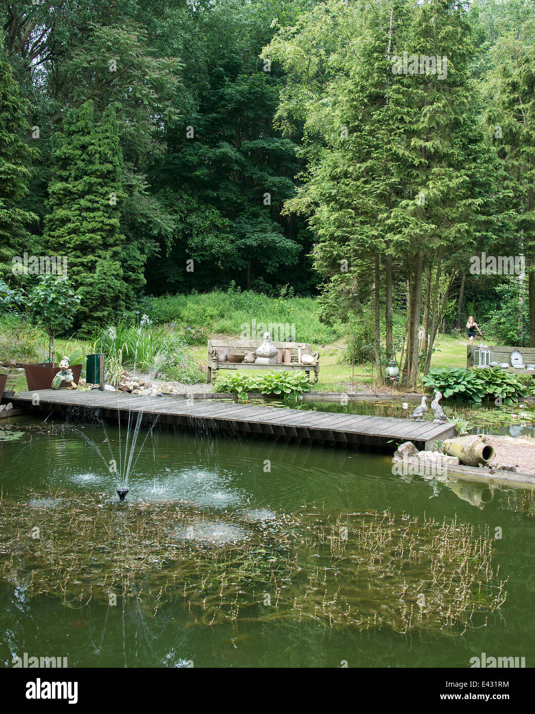 english garden with pond water bridge seat and old vases Stock Photo