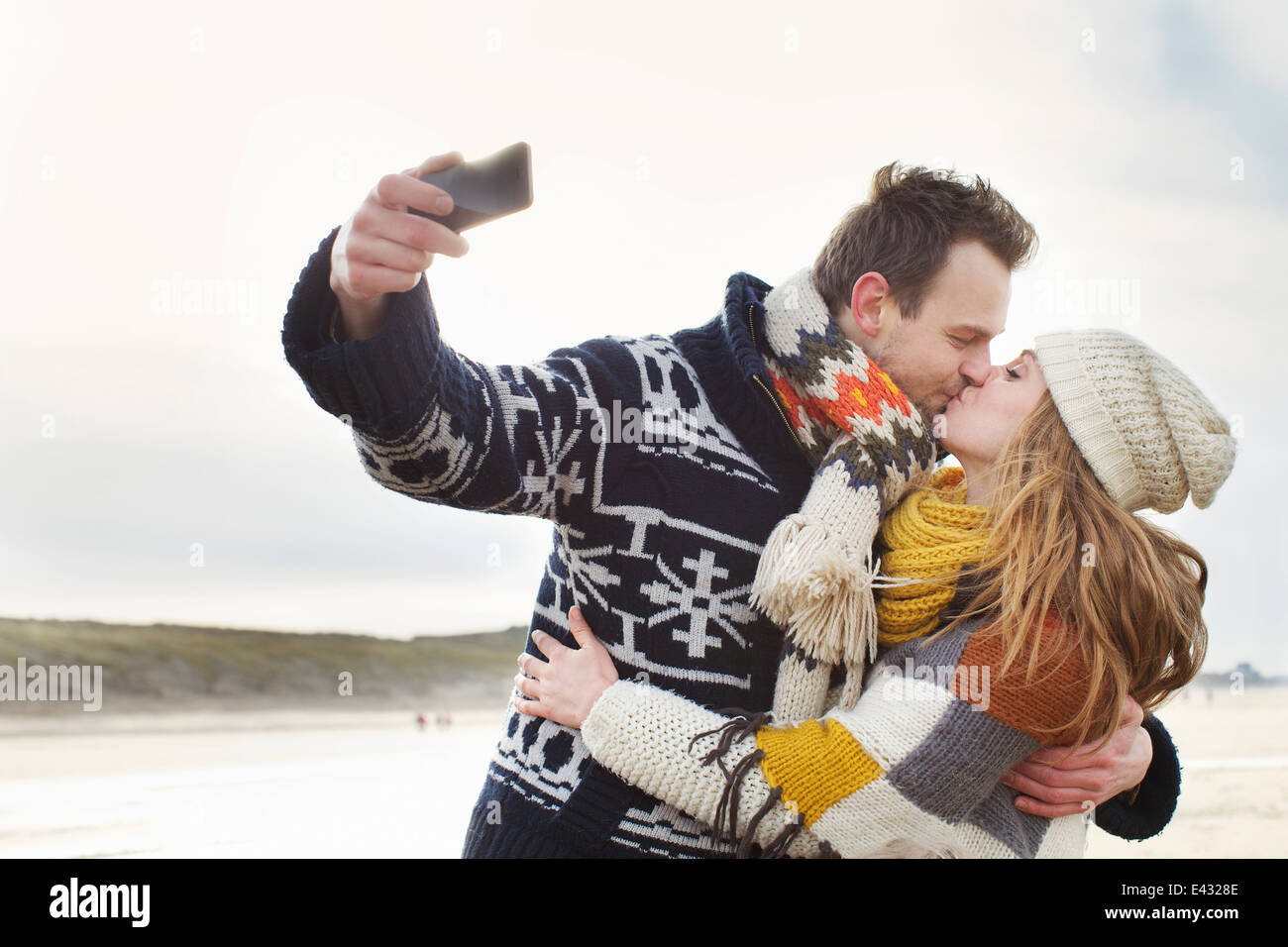 Mid adult couple taking self portrait with smartphone on beach, Bloemendaal aan Zee, Netherlands Stock Photo