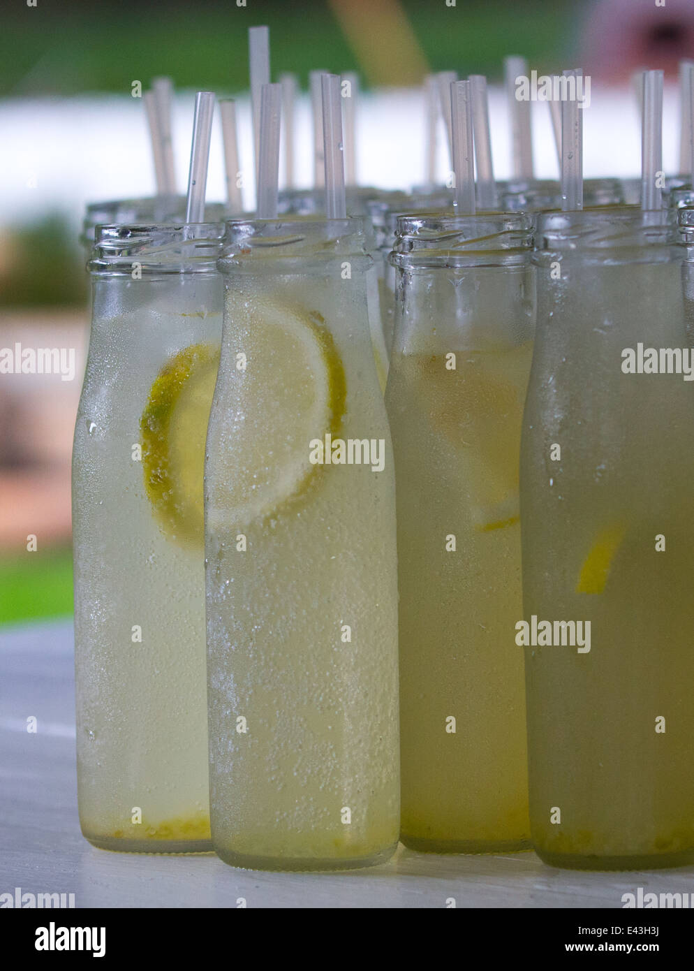 Plenty of glass bottles with ginger beer and lemon slices in it. Straws sticking out on top. Stock Photo