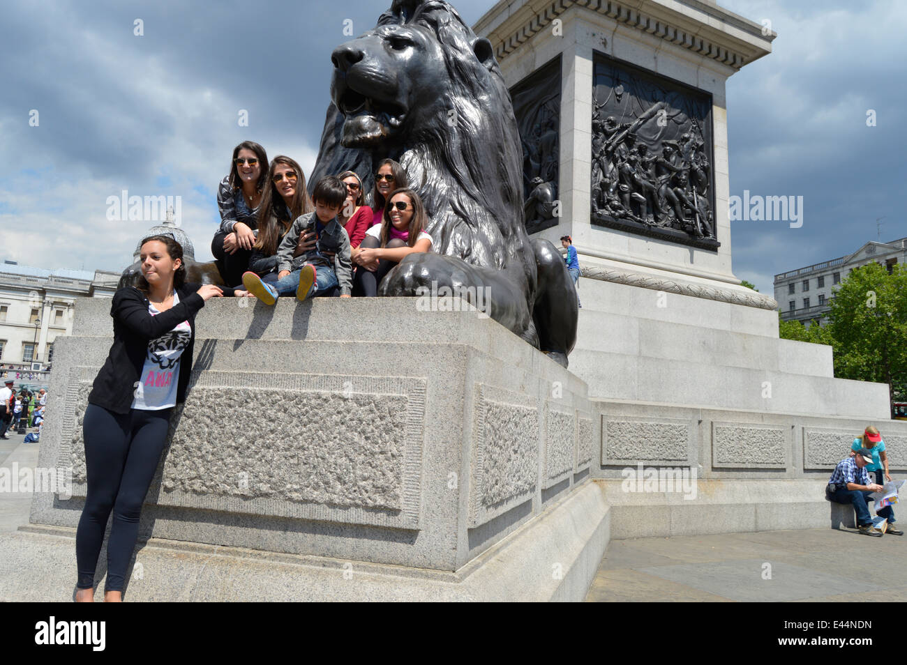 Lion statue with tourists in Trafalgar square,London,UK Stock Photo