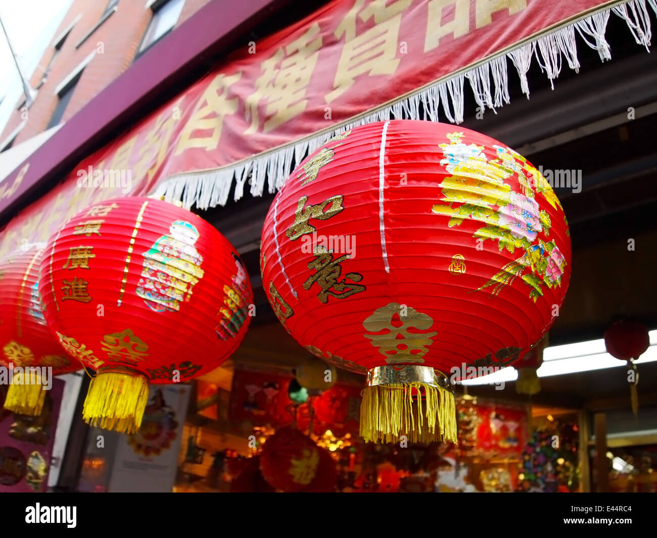 A few brightly decorated red paper Chinese lanterns hang in the front of a souvenir shop in