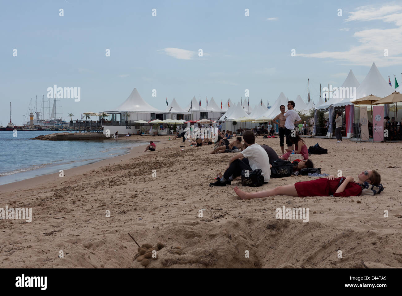 Beach with sunbathing woman and festival goers at the Cannes film festival in Cannes, France. Stock Photo