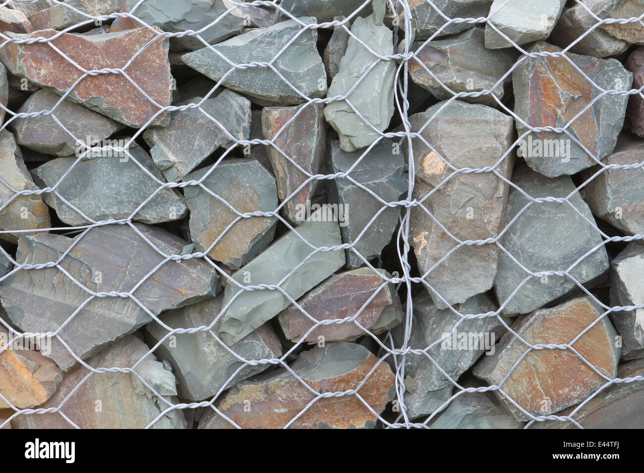 Rock fence with split rock and hexagonal like wire similar to chicken wire. Stock Photo