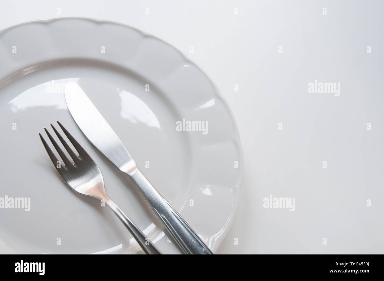 Fork and knife on an empty plate. Close view. Stock Photo