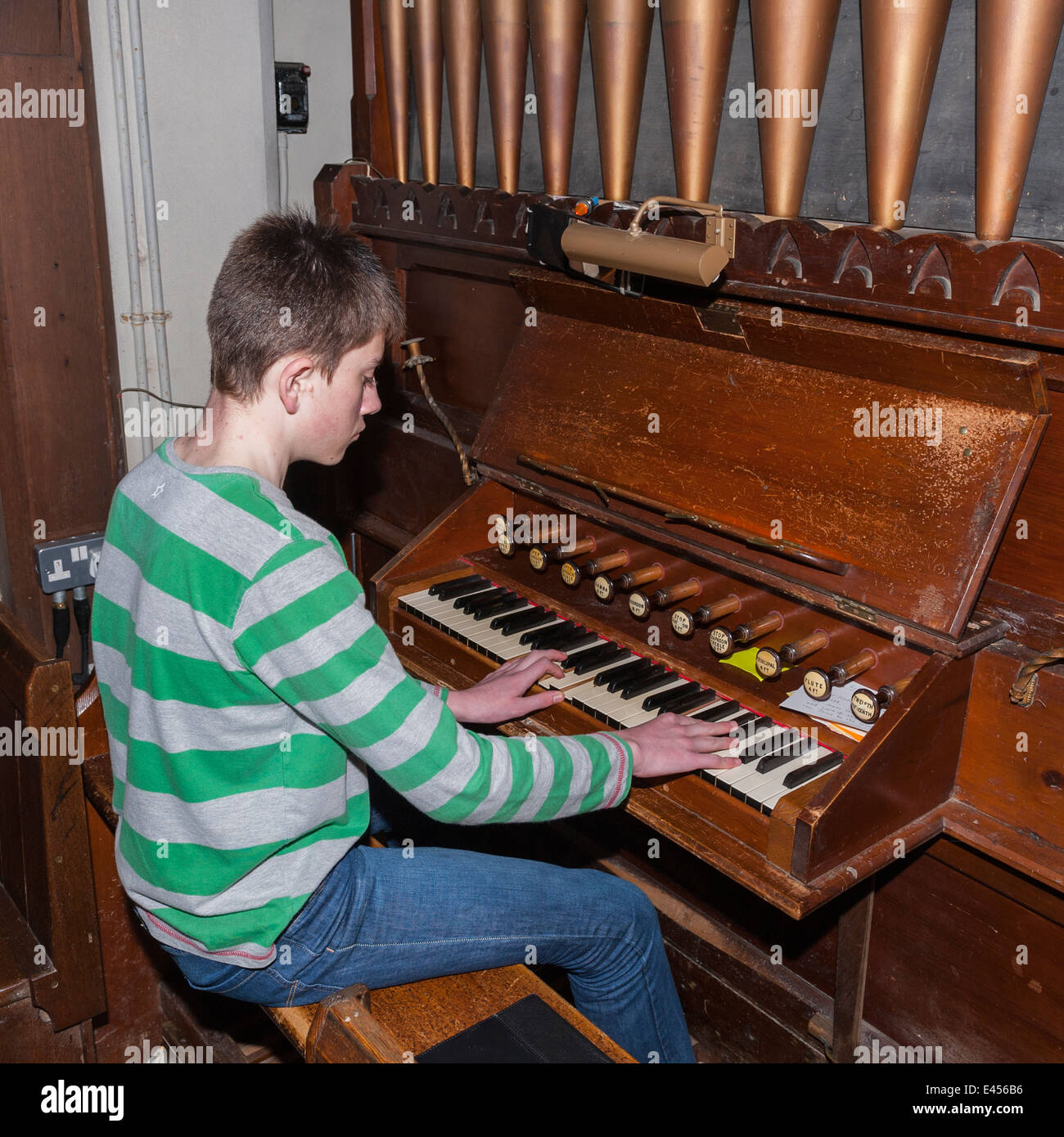 A 14 year old boy playing a pipe organ inside a UK church Stock Photo
