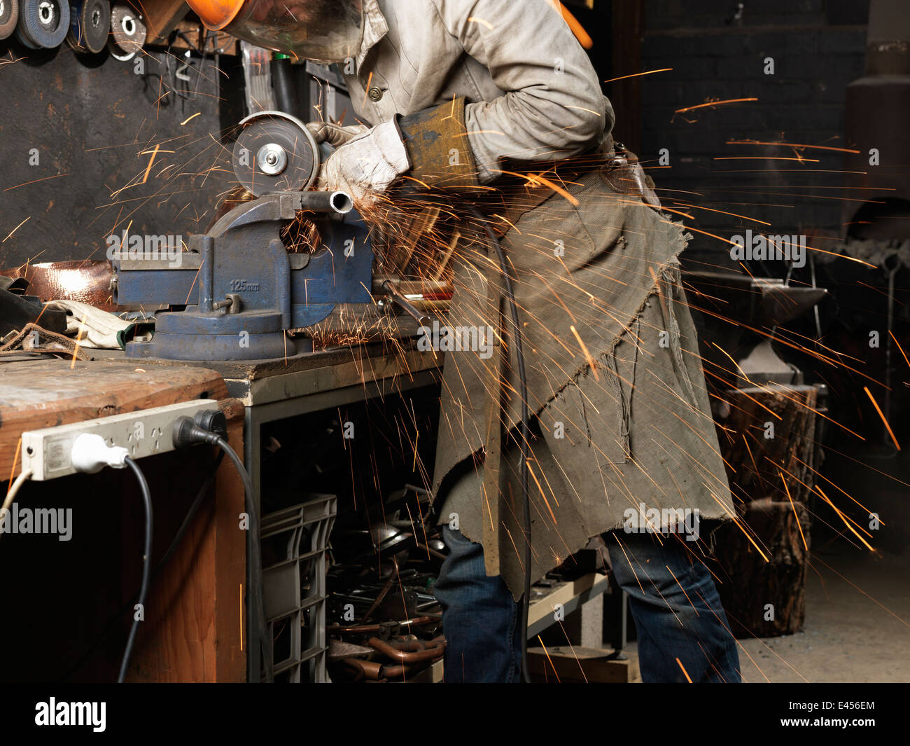 Blacksmith grinding metal on a machine in workshop Stock Photo